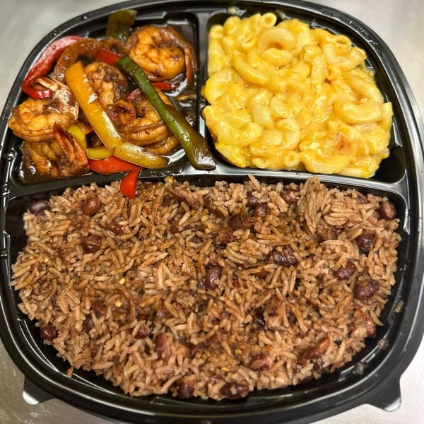 A Jamaican meal with jerk shrimp, mac and cheese, and rice and peas in a black to-go container.
